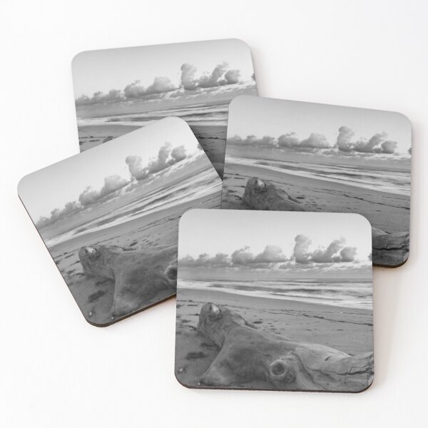 Item preview, A large piece of driftwood lies on a sandy beach, surrounded by scattered seaweed and set against a backdrop of rolling ocean waves designed and sold by EyezWatchin.