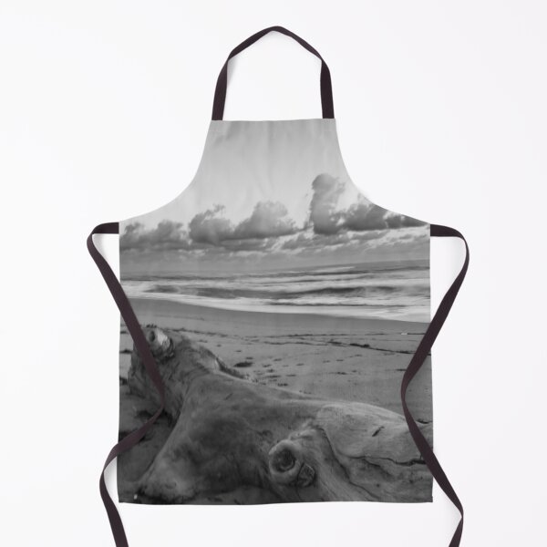 Item preview, A large piece of driftwood lies on a sandy beach, surrounded by scattered seaweed and set against a backdrop of rolling ocean waves designed and sold by EyezWatchin.