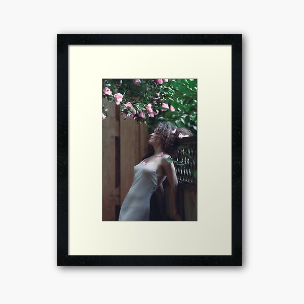 Item preview, Tranquil sensual portrait of a beautiful woman under a pink camellia with fallen flower petals in her long curly hair and on her chest art photo print designed and sold by AwenArtPrints.