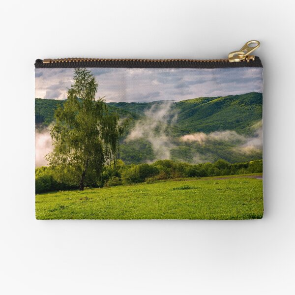 fog rising behind the forest on a hillside Zipper Pouch