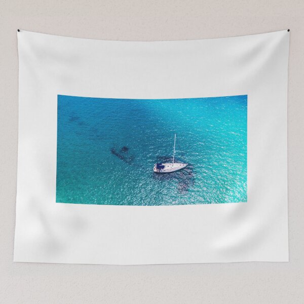 Item preview, Yacht anchoring in crystal clear turquoise water in front of the tropical island, alternative lifestyle, living on a boat. Aerial view of yacht at anchor on turquoise water, showing luxury, wealth. designed and sold by Framed Horizons.