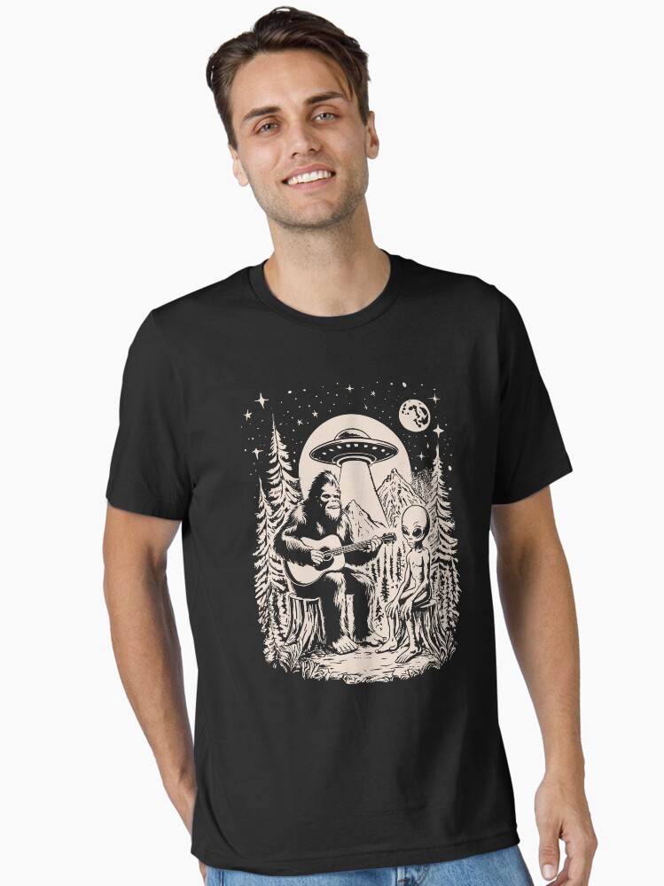 Thumbnail 1 of 7, Essential T-Shirt, Bigfoot Playing Guitar With Alien UFO Vintage Camping designed and sold by CutenessKlub.