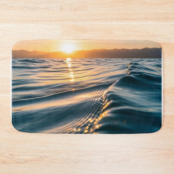 Item preview, Waves shimmer on the water's surface as the sun sets over distant mountains, creating a warm, golden glow designed and sold by homydesign.