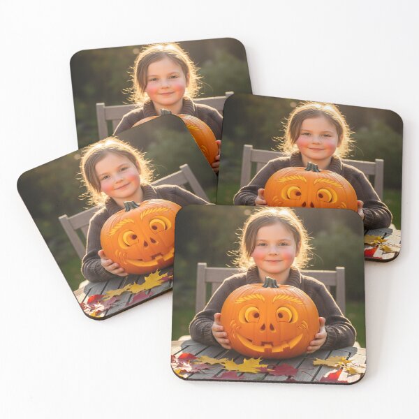 Item preview, A cheerful young girl with rosy cheeks is happily holding a carved pumpkin at a wooden table covered in fallen autumn leaves designed and sold by homydesign.