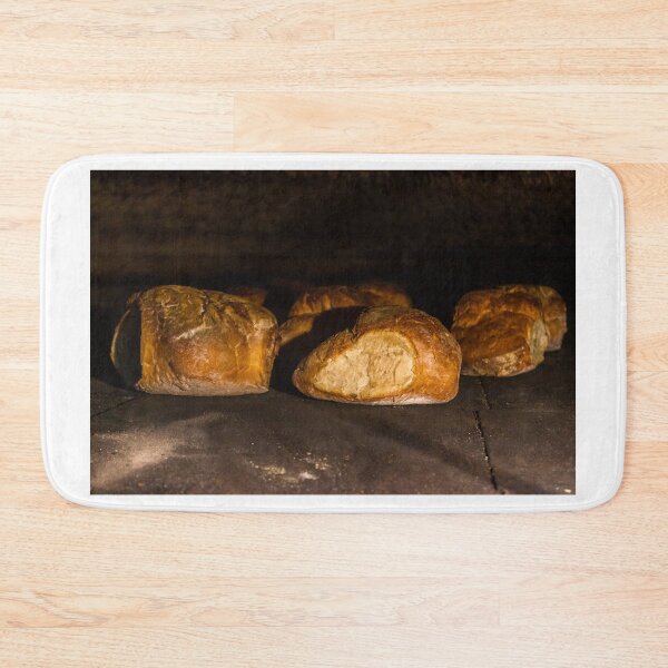 Item preview, Warm Baked Bread Rolls Resting On Dark Stone Surface In Low Lighting designed and sold by Nmallia.