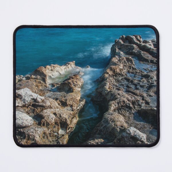 Item preview, Sunlit Turquoise Ocean Crashing Against Rugged Coastal Rocks in a Serene Seascape designed and sold by Nmallia.