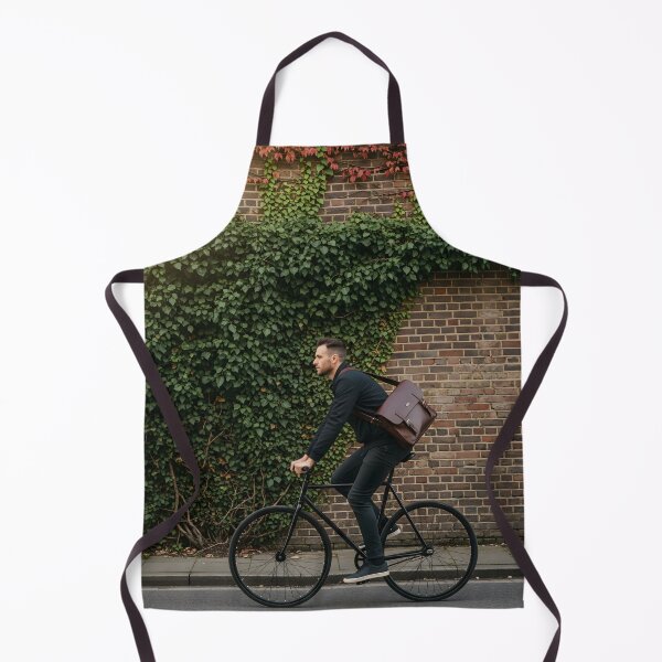 Item preview, Stylish man riding a bicycle in profile past a brick wall covered in ivy designed and sold by homydesign.