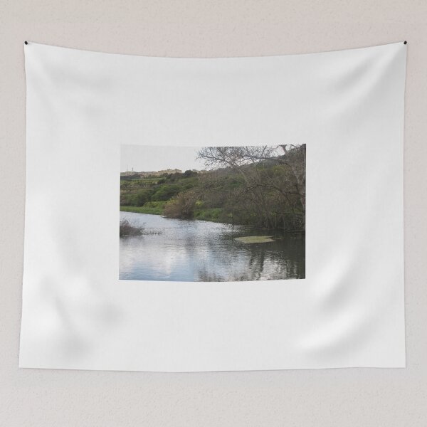 Item preview, Tranquil Lake Bordering Green Hills With Bare Trees and a Village in the Background designed and sold by Nmallia.