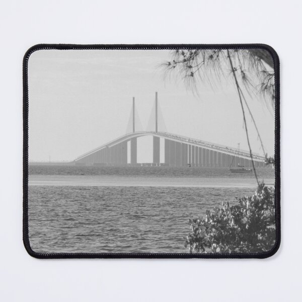 Item preview, A vibrant sunrise casts a golden glow over the Sunshine Skyway Bridge, perfectly framed by lush foliage and silhouetted trees designed and sold by EyezWatchin.