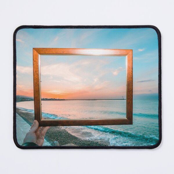 Item preview, Hand holding a wooden frame capturing a vibrant sunset view over the turquoise ocean. designed and sold by MDB_Shop.