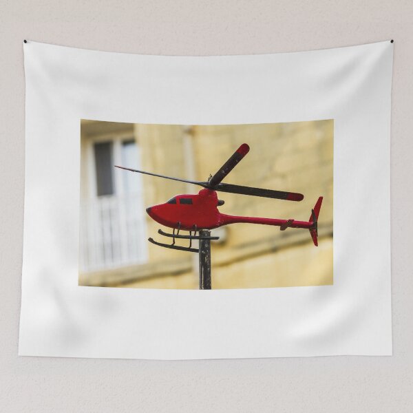 Item preview, Red Model Helicopter Weather Vane On Post With Blurred Urban Background In Sunlit City designed and sold by Nmallia.
