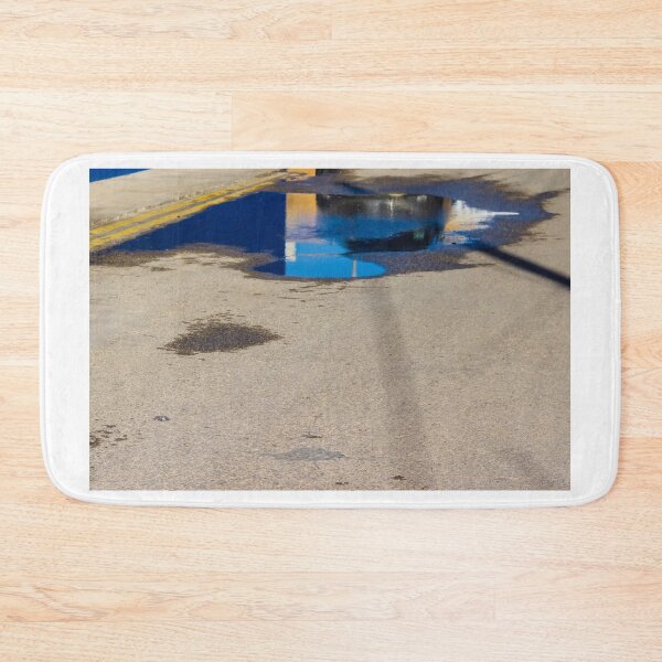 Item preview, Puddle On Wet Road Surface Reflects Buildings In Bright Urban Street Scene designed and sold by Nmallia.