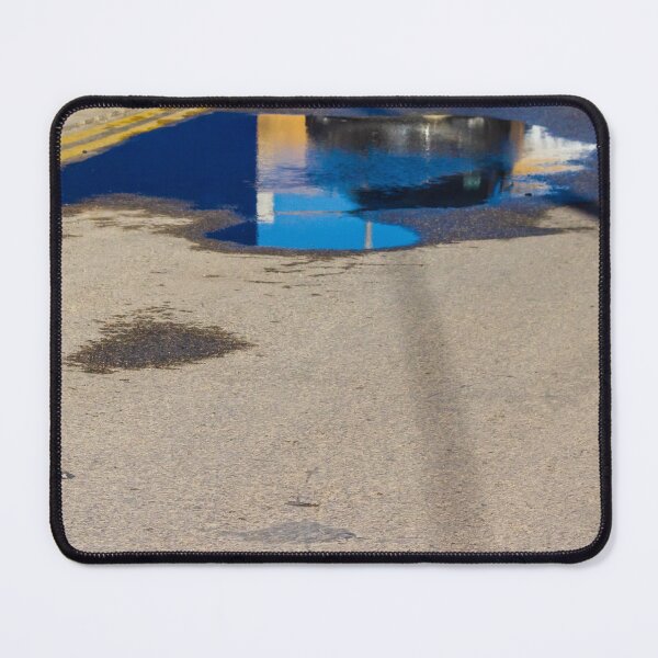 Item preview, Puddle On Wet Road Surface Reflects Buildings In Bright Urban Street Scene designed and sold by Nmallia.