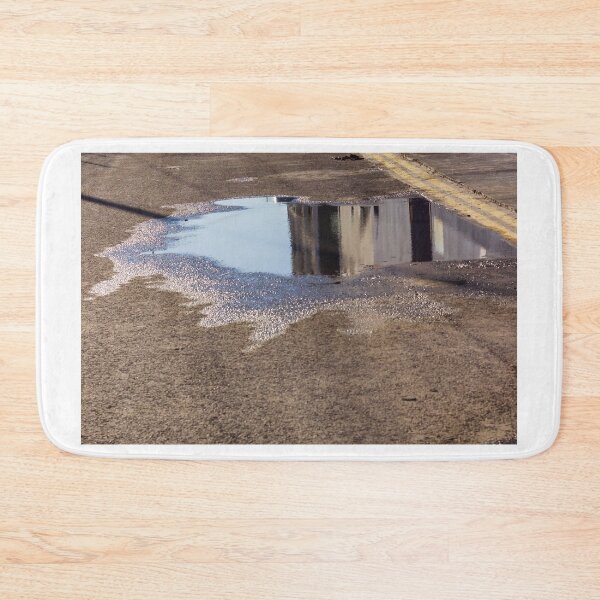 Item preview, Puddle On Wet Road Surface Reflects Buildings In Bright Urban Street Scene designed and sold by Nmallia.
