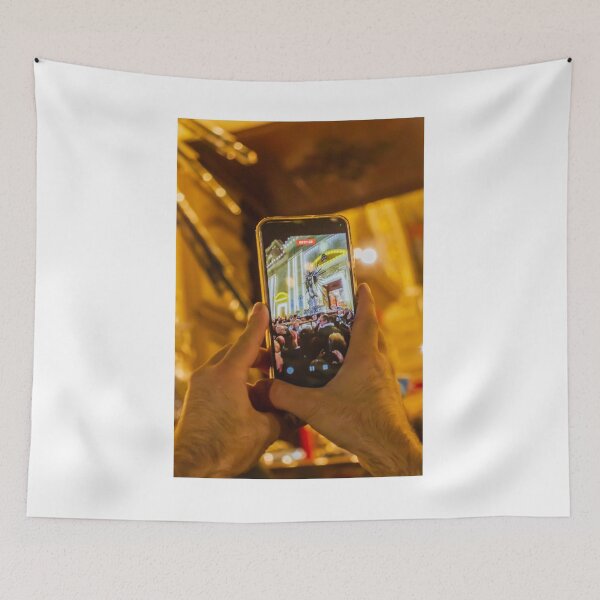 Item preview, Person Capturing Large Night Crowd At Decorative City Event On Smartphone With Festive Lighting And Architecture designed and sold by Nmallia.