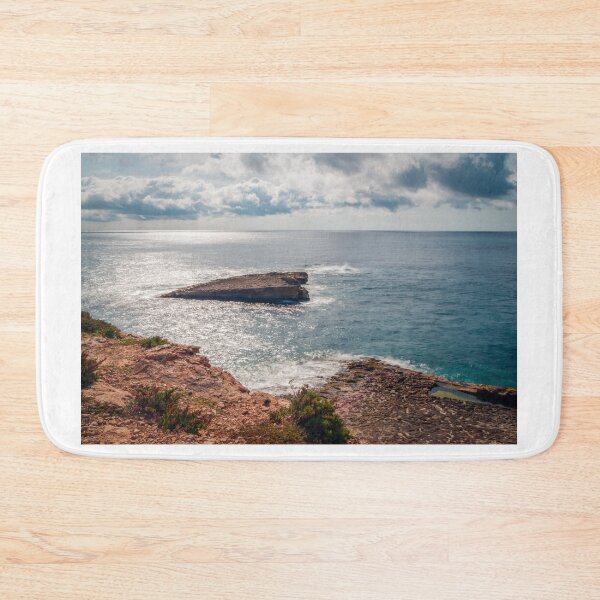 Item preview, Sunlit Rocky Coastline and Small Island Under Cloudy Sky With Calm Blue Sea and Sparkling Horizon designed and sold by Nmallia.