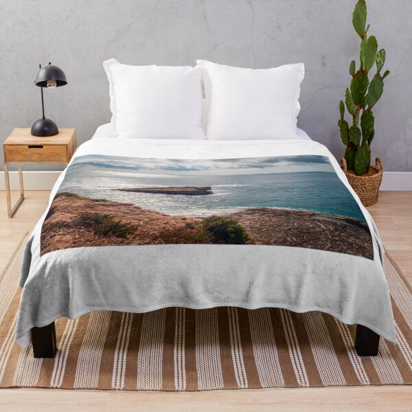 Item preview, Sunlit Rocky Coastline and Small Island Under Cloudy Sky With Calm Blue Sea and Sparkling Horizon designed and sold by Nmallia.