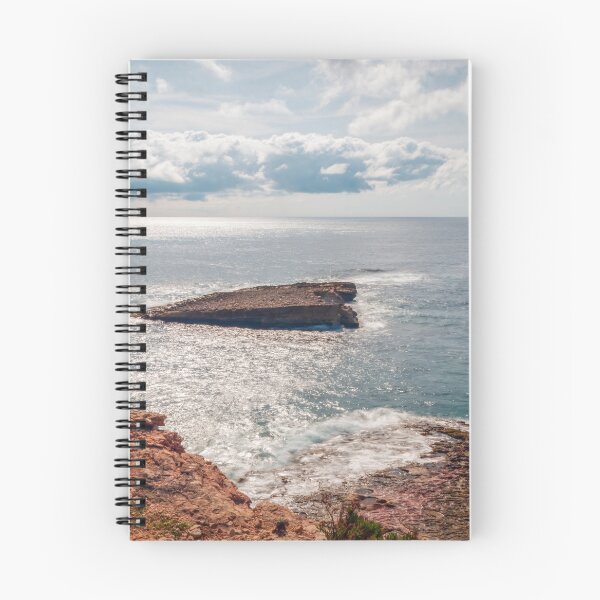 Item preview, Sunlit Rocky Coastline and Small Offshore Island Under Cloudy Sky Over Calm Blue Ocean designed and sold by Nmallia.