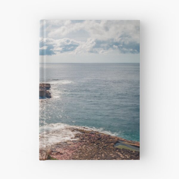 Item preview, Sunlit Rocky Coastline and Small Offshore Island Under Cloudy Sky Over Calm Blue Ocean designed and sold by Nmallia.