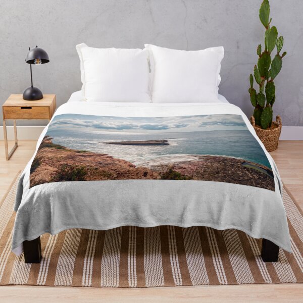 Item preview, Sunlit Rocky Coastline and Small Offshore Island Under Cloudy Sky Over Calm Blue Ocean designed and sold by Nmallia.