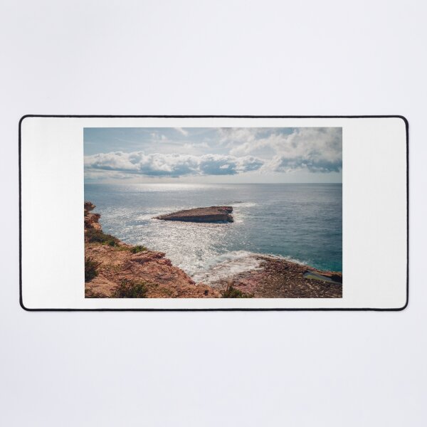 Item preview, Sunlit Rocky Coastline and Small Offshore Island Under Cloudy Sky Over Calm Blue Ocean designed and sold by Nmallia.