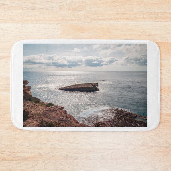 Item preview, Sunlit Rocky Coastline With Small Sea Stack and Calm Ocean Under a Cloudy Sky designed and sold by Nmallia.