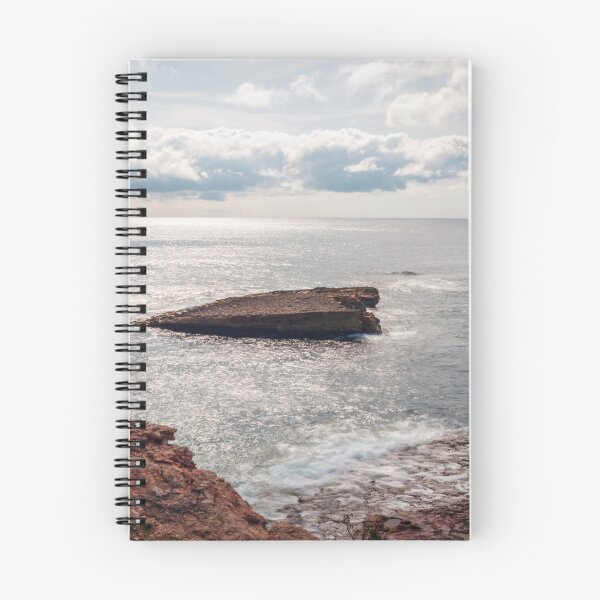 Item preview, Sunlit Rocky Coastline With Small Sea Stack and Calm Ocean Under a Cloudy Sky designed and sold by Nmallia.
