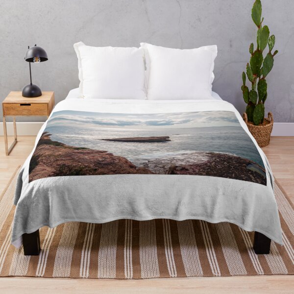 Item preview, Sunlit Rocky Coastline With Small Sea Stack and Calm Ocean Under a Cloudy Sky designed and sold by Nmallia.