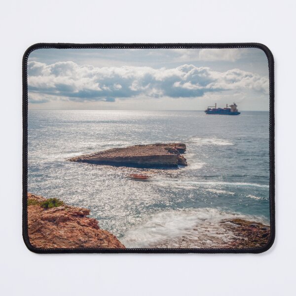 Item preview, Sunlit Rocky Coastline With Cargo Ship on Calm Sea Under Dramatic Cloudy Sky designed and sold by Nmallia.