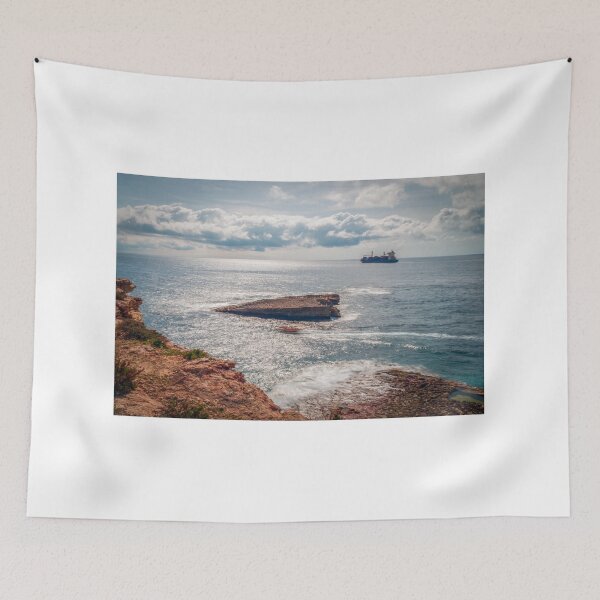 Item preview, Sunlit Rocky Coastline With Cargo Ship on Calm Sea Under Dramatic Cloudy Sky designed and sold by Nmallia.