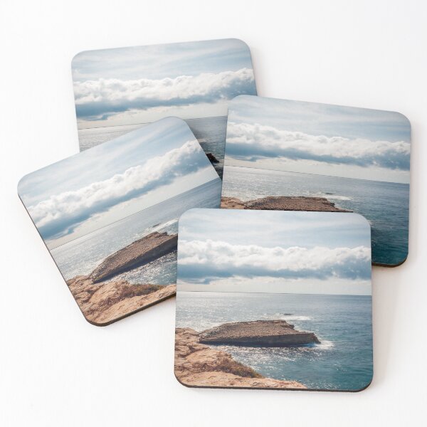 Item preview, Sunlit Rocky Coastline Over Calm Blue Ocean With Dramatic Cloud Horizon And Serene Seascape View designed and sold by Nmallia.