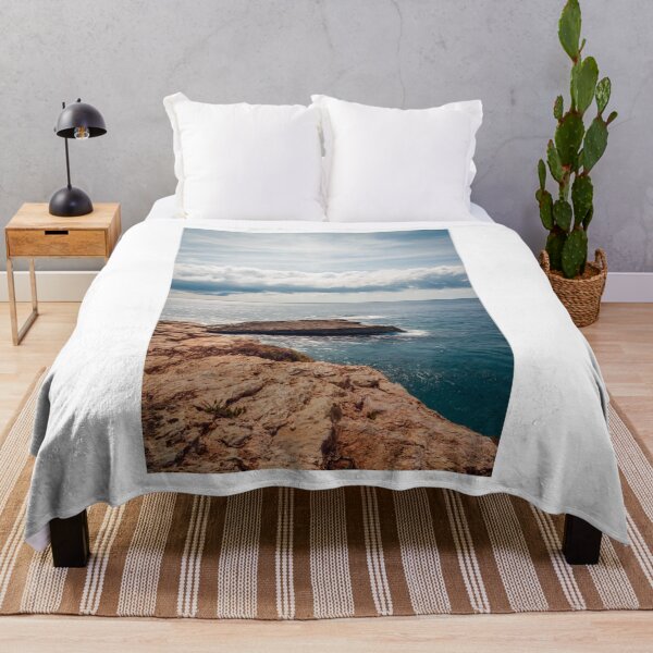 Item preview, Sunlit Rocky Coastline Over Calm Blue Ocean With Dramatic Cloud Horizon And Serene Seascape View designed and sold by Nmallia.