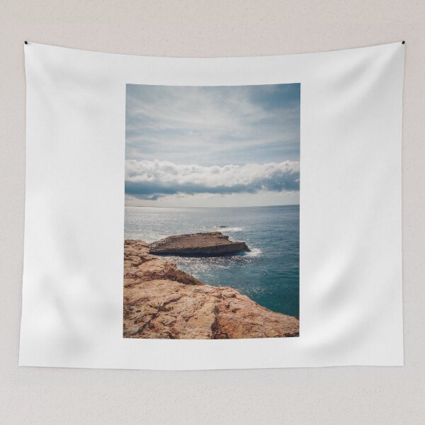 Item preview, Sunlit Rocky Coastline Over Calm Blue Ocean With Dramatic Cloud Horizon And Serene Seascape View designed and sold by Nmallia.