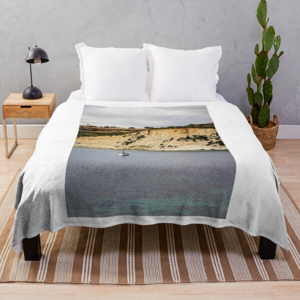 Item preview, Sailboat Anchored Below Dramatic Limestone Cliffs Along Quiet Coastal Bay Under Overcast Sky designed and sold by Nmallia.