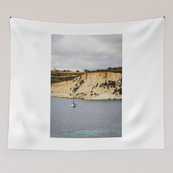 Item preview, Sailboat Anchored Below Dramatic Limestone Cliffs Along Quiet Coastal Bay Under Overcast Sky designed and sold by Nmallia.