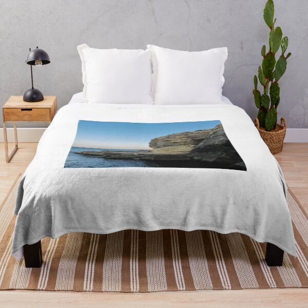 Item preview, Sunlit Coastal Cliffs Over Calm Blue Sea With Rocky Shoreline and Clear Sky Landscape designed and sold by Nmallia.
