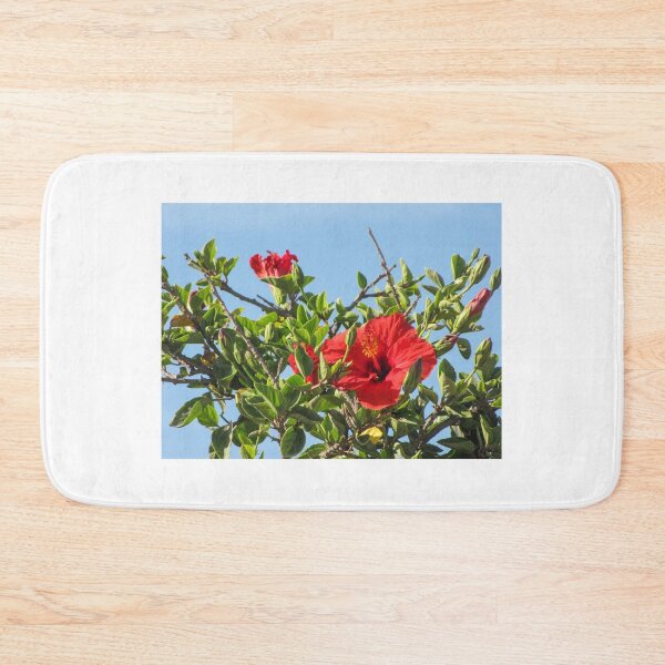 Item preview, Vibrant Red Hibiscus Blossom On Green Shrub Branches Against Clear Blue Sky Close-Up designed and sold by Nmallia.
