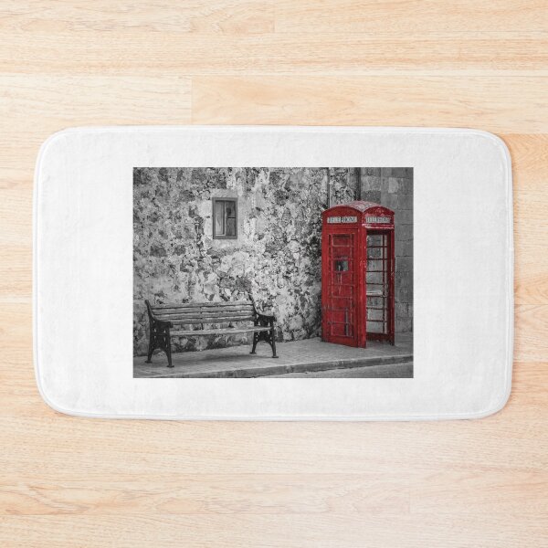 Item preview, Red Telephone Box and Empty Bench Against Weathered Stone Wall in Selective Color Photograph designed and sold by Nmallia.