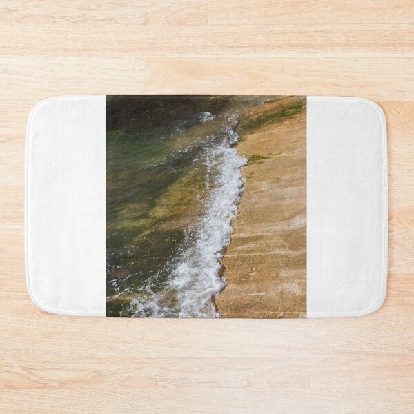 Item preview, Gentle Wave Lapping Against Rocky Shore With Sea Foam and Algae on Sunlit Coastline designed and sold by Nmallia.