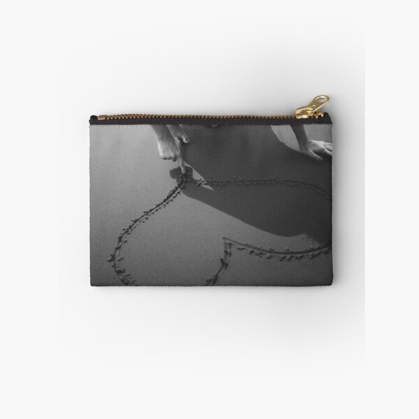 Item preview, Drawing heart in the sand at the beach black and white romantic photographic art print designed and sold by Astrid Arkhangelsky.