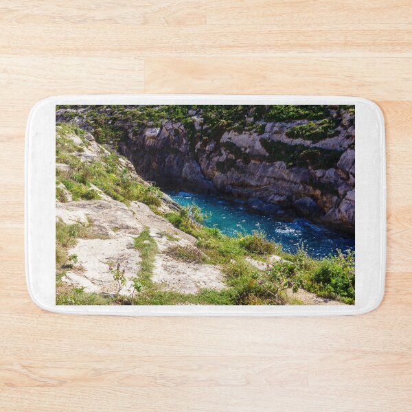 Item preview, Sunlit Rocky Coastal Inlet With Turquoise Water, Wildflowers and Rugged Limestone Cliffs designed and sold by Nmallia.