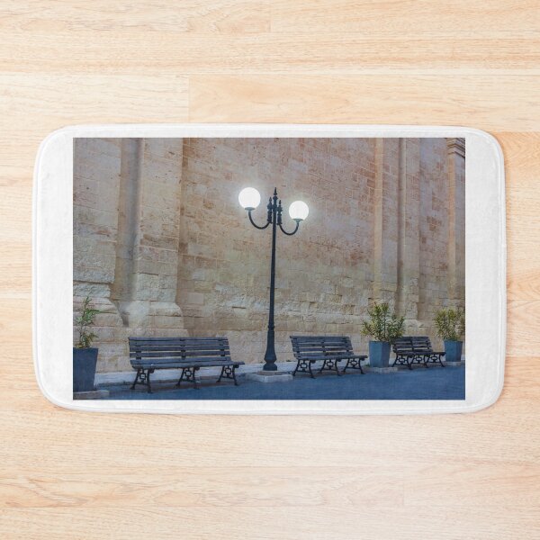 Item preview, Historic Stone Wall With Lamppost and Empty Benches Along Quiet Urban Street at Dusk designed and sold by Nmallia.