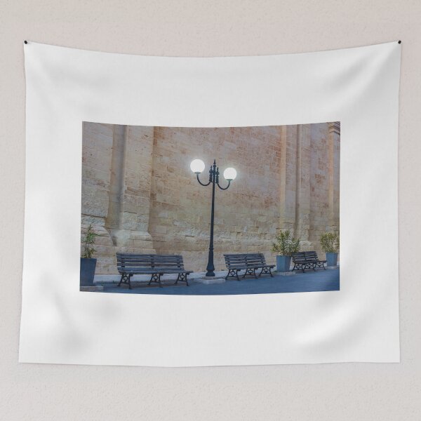 Item preview, Historic Stone Wall With Lamppost and Empty Benches Along Quiet Urban Street at Dusk designed and sold by Nmallia.