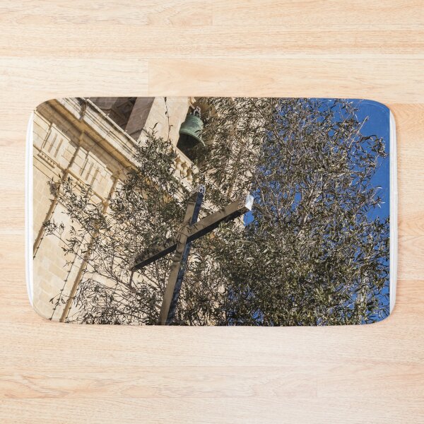 Item preview, Wooden Cross and Olive Tree in Front of Historic Church Bell Tower Against Blue Sky designed and sold by Nmallia.