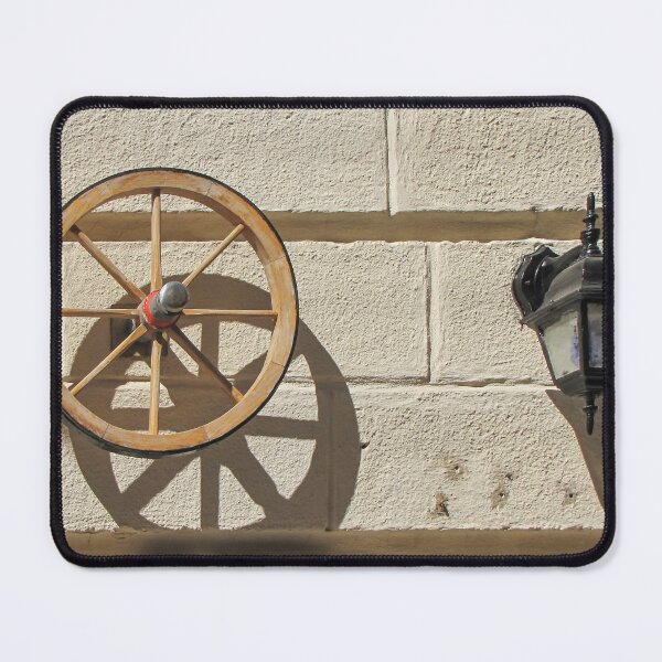 Item preview, Vintage Wooden Wheel and Lantern Mounted on Sunlit Stone Wall Casting Strong Shadow designed and sold by Nmallia.