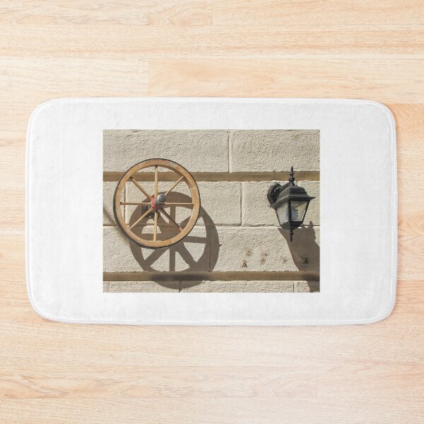 Item preview, Vintage Wooden Wheel and Lantern Mounted on Sunlit Stone Wall Casting Strong Shadow designed and sold by Nmallia.