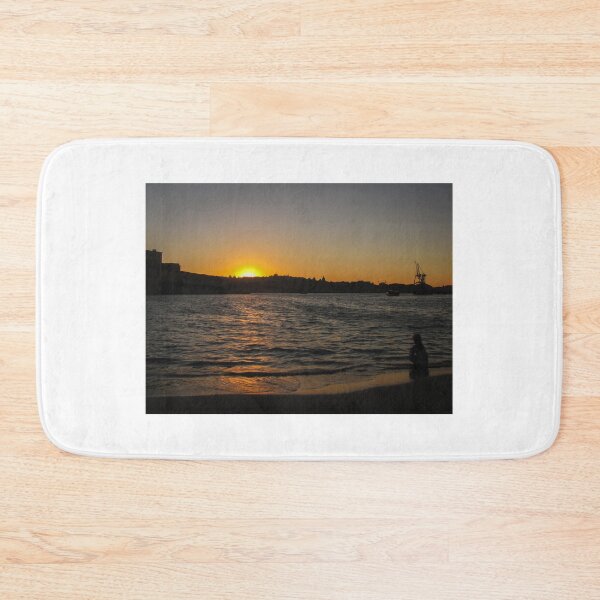 Item preview, Sunset Over Harbor Beach With Silhouette Child Sitting on Shore and City Skyline Beyond designed and sold by Nmallia.