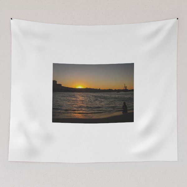 Item preview, Sunset Over Harbor Beach With Silhouette Child Sitting on Shore and City Skyline Beyond designed and sold by Nmallia.