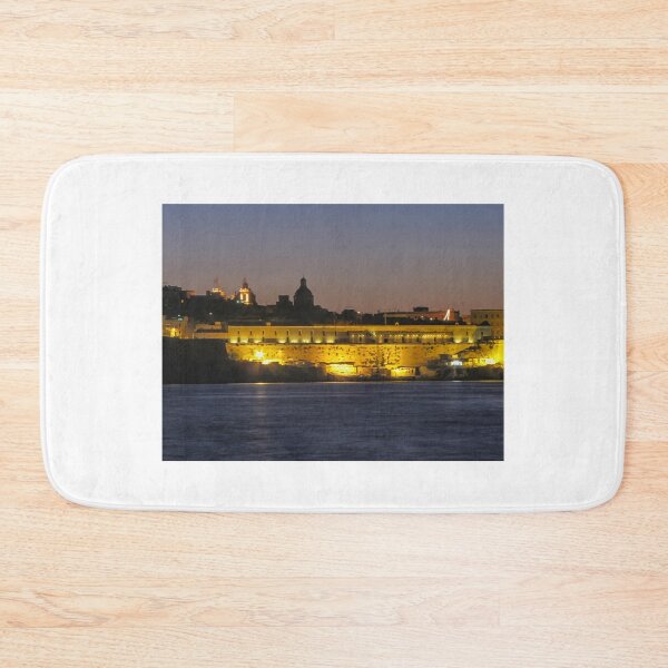 Item preview, Illuminated Coastal Fortress at Dusk Over Calm Harbor Water With Historic City Silhouette designed and sold by Nmallia.