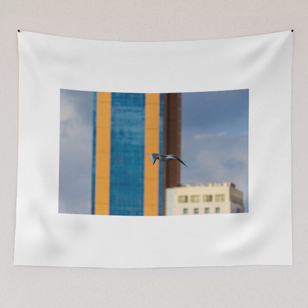 Item preview, Seagull In Flight Over Urban Cityscape With Colorful High-Rise Buildings And Cloudy Sky designed and sold by Nmallia.